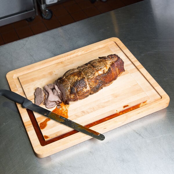 A piece of meat being cut on a Tablecraft wood cutting board.