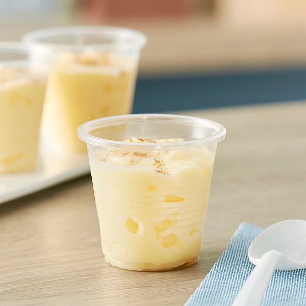 A close-up of a translucent Choice plastic cup of pudding.