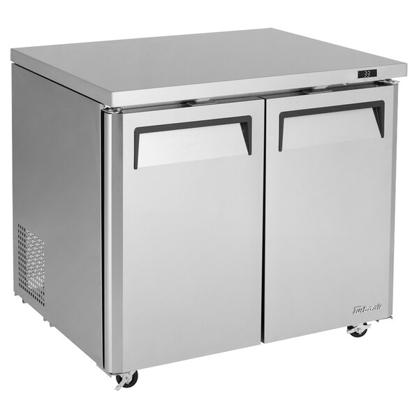 A silver Turbo Air undercounter refrigerator with two black doors.