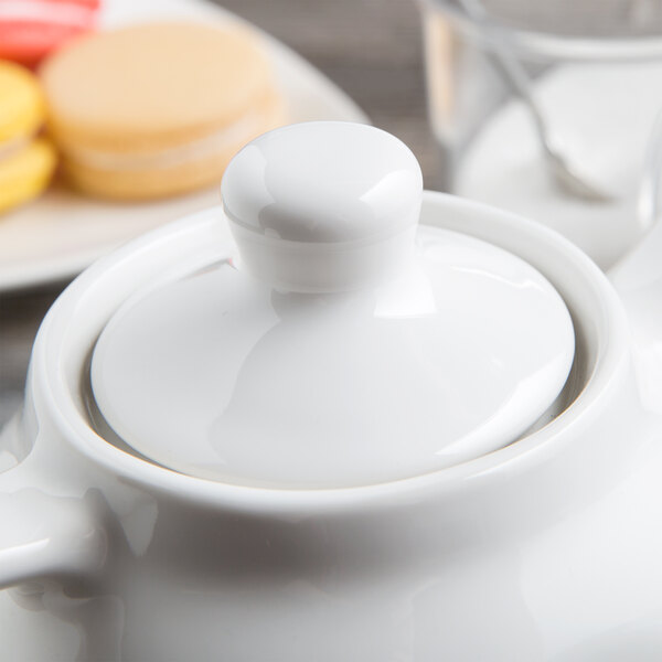 A white Tuxton china teapot with a lid on a white background.