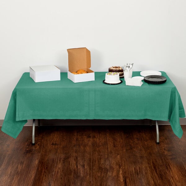 A table with a Creative Converting Hunter Green Tissue / Poly Table Cover and food on it.