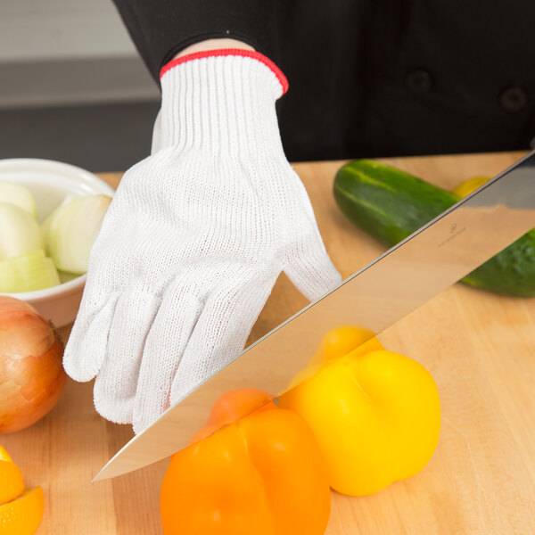 A person wearing a Victorinox cut resistant glove cutting a yellow bell pepper.