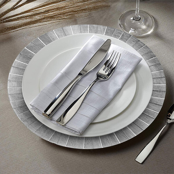A white plastic charger plate with a silver geometric design.