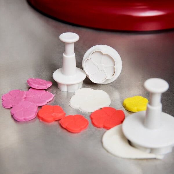 A white plastic Ateco flower cutter set with colorful flowers.