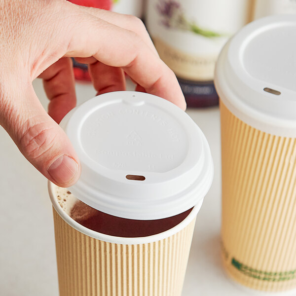 A hand holding a white EcoChoice translucent paper hot cup lid over a cup of coffee.
