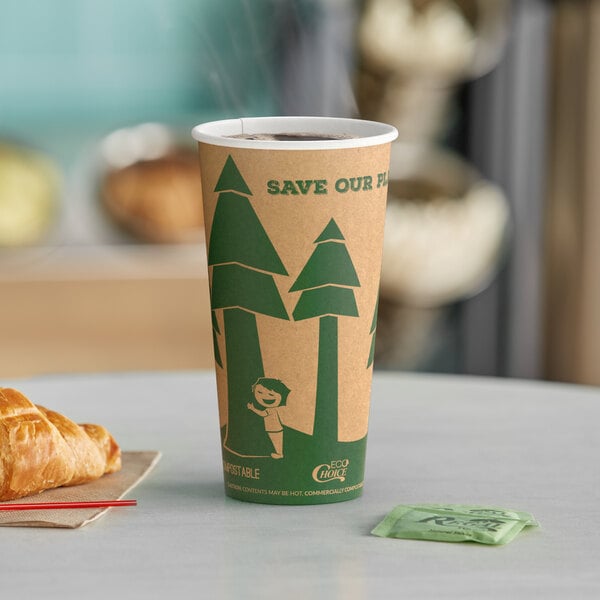 A close-up of a brown EcoChoice paper hot cup with green trees printed on it on a table with a croissant and coffee.