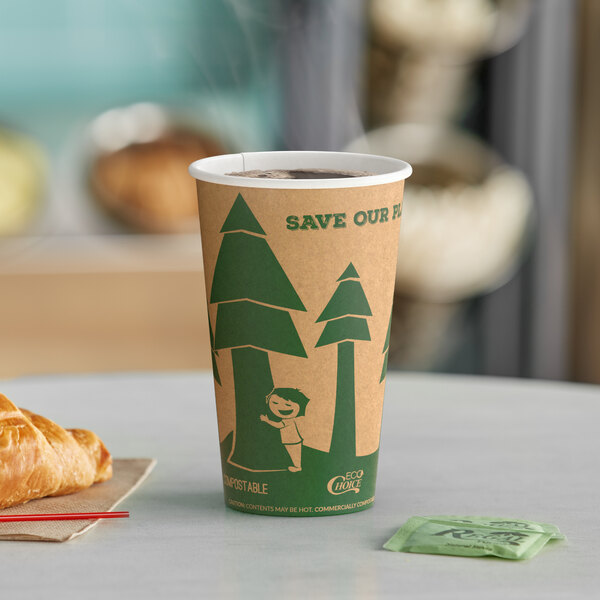 A close-up of a EcoChoice Kraft paper hot cup with a tree print on a table with a cup of coffee and croissant.