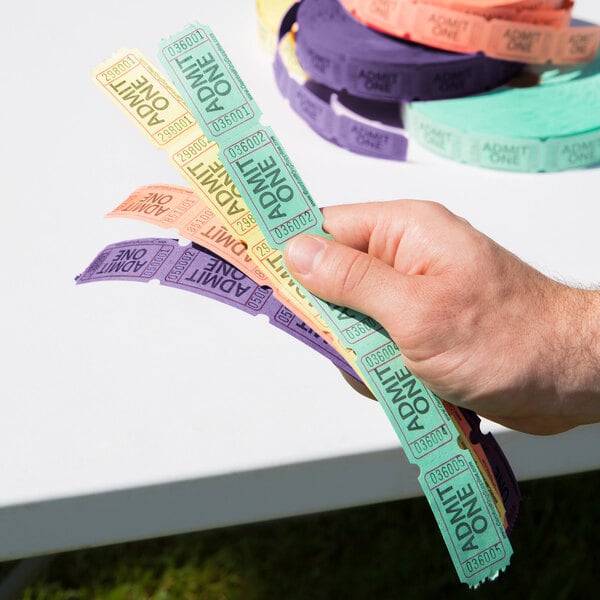A hand holding Carnival King Admit One tickets in green, orange, purple, and yellow.