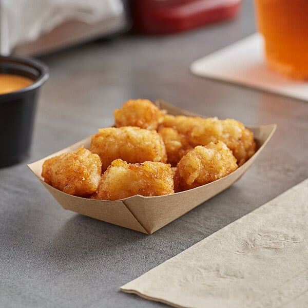 A close up of tater tots in a black Bagcraft Packaging paper food tray.