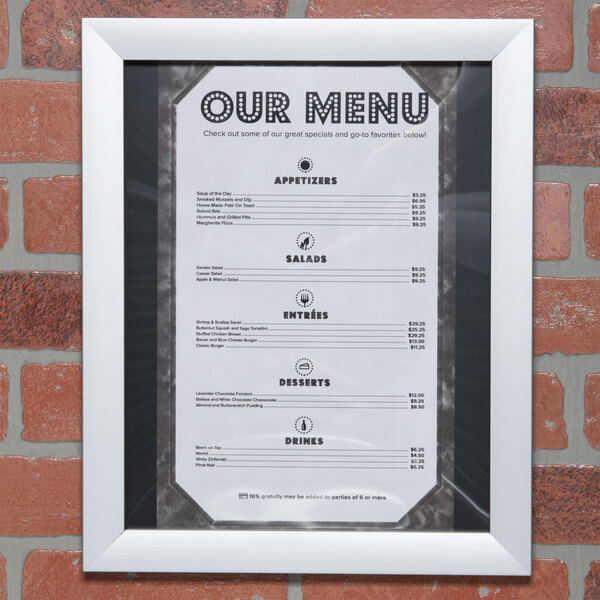 An Aarco satin aluminum snap frame holding a menu on a brick wall.