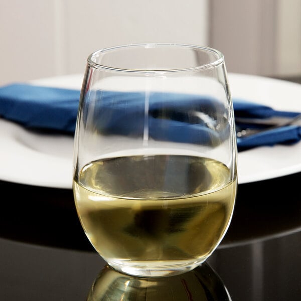 A Libbey stemless wine glass filled with white wine on a table.