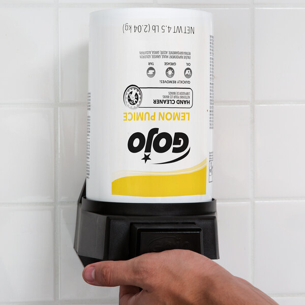 A hand holding a white container of GOJO Lemon Pumice Hand Cleaner with a black and yellow label.