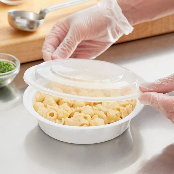 A person in white gloves opening a Choice white microwavable container of macaroni and cheese.