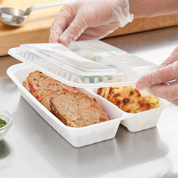 A person holding a Choice 3-compartment rectangular microwavable container with meatloaf in it.