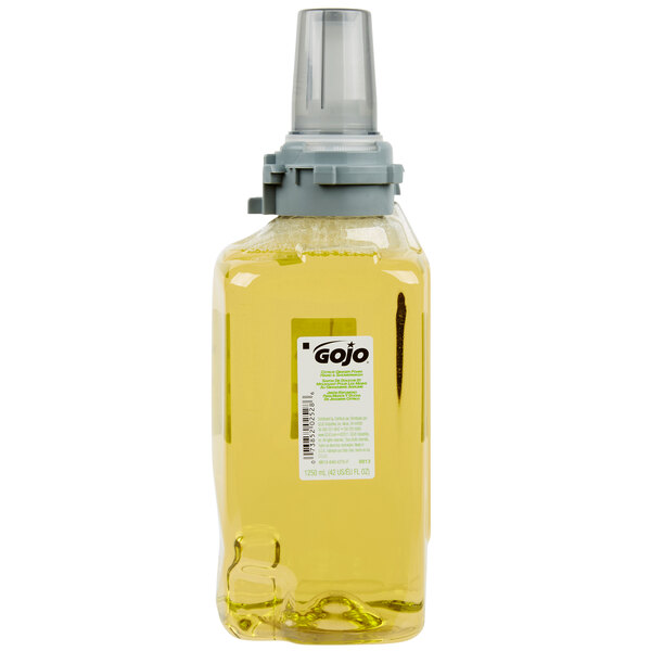 A bottle of GOJO Citrus Ginger foam hand soap with a grey lid filled with yellow liquid.