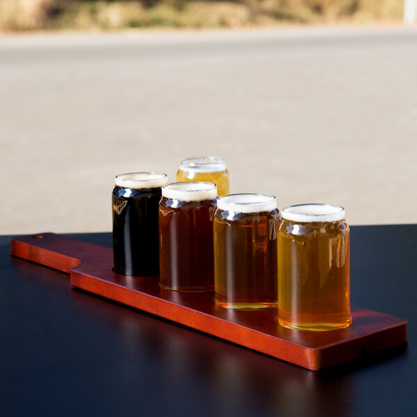 A row of Libbey Mini Can Tasting Glasses on a wooden board with a Mahogany finish.