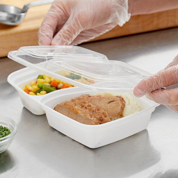 A person in gloves holding a white Choice rectangular plastic container with food in it.