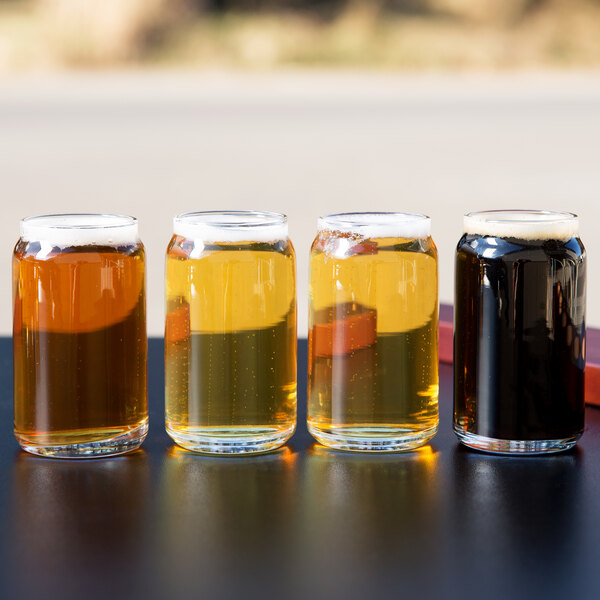 A group of Libbey glass can tasting glasses filled with beer on a table.