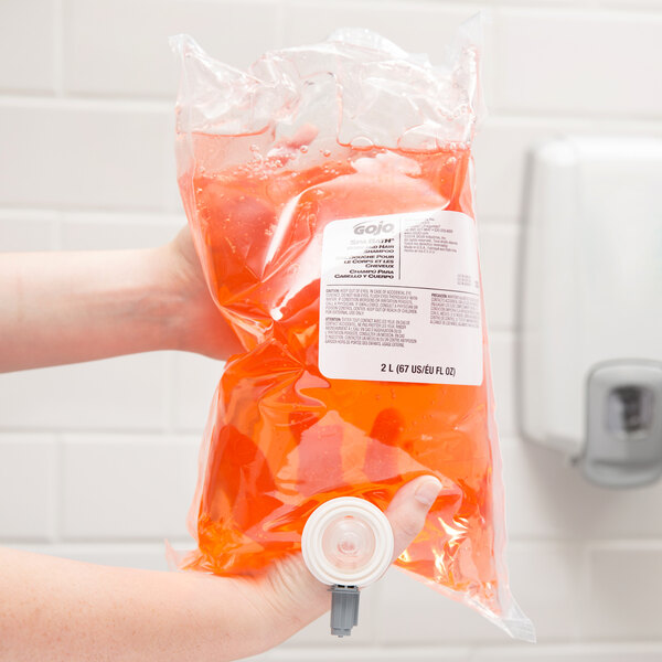 A person holding a bag of orange GOJO liquid