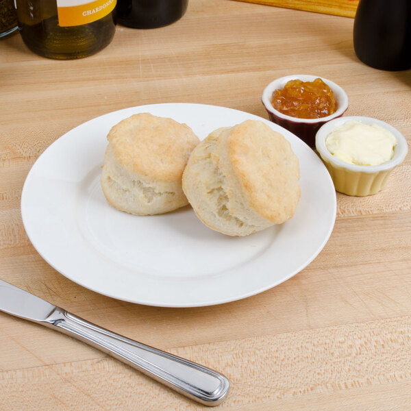 A plate with two biscuits and butter on it.