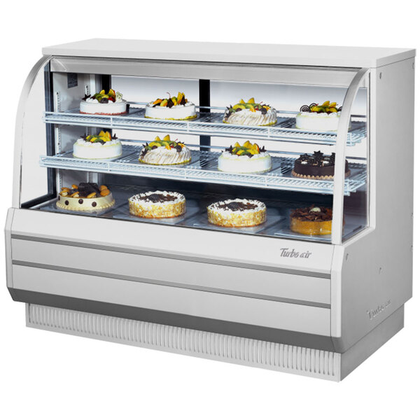 A white Turbo Air dry bakery display case with cakes and pies on it.