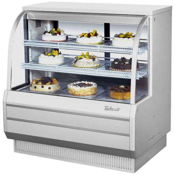 A white Turbo Air refrigerated bakery display case filled with cakes.