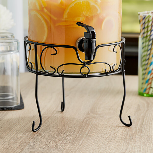 An Acopa beverage dispenser with orange liquid on a table.