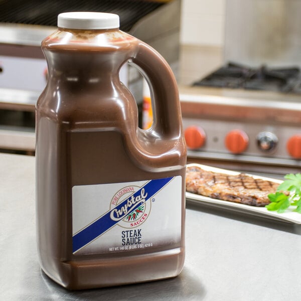 A Crystal 1 gallon bottle of steak sauce on a counter.