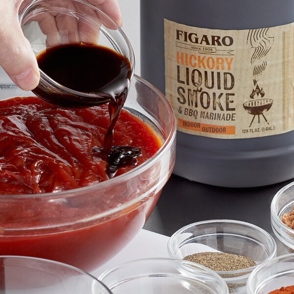 A person pouring Figaro Hickory Liquid Smoke and Marinade into a white bowl.