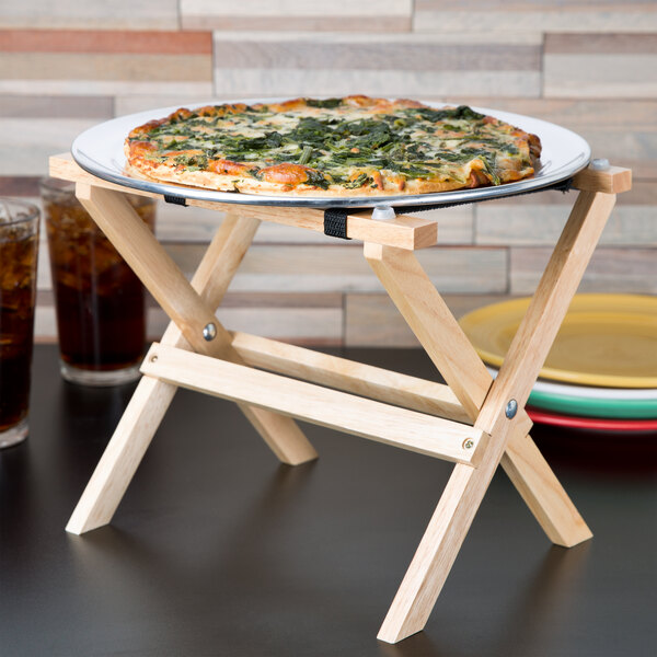 A pizza on a Tablecraft mini table tray stand with drinks on a wooden table.