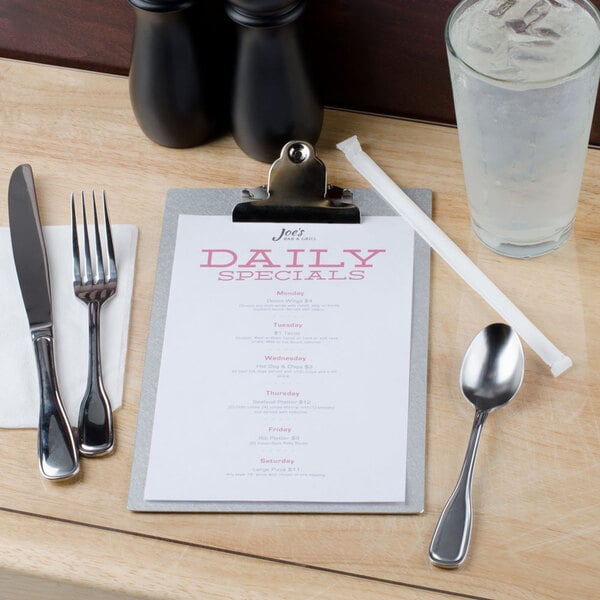 A Menu Solutions Alumitique clipboard with a menu on a table next to silverware.