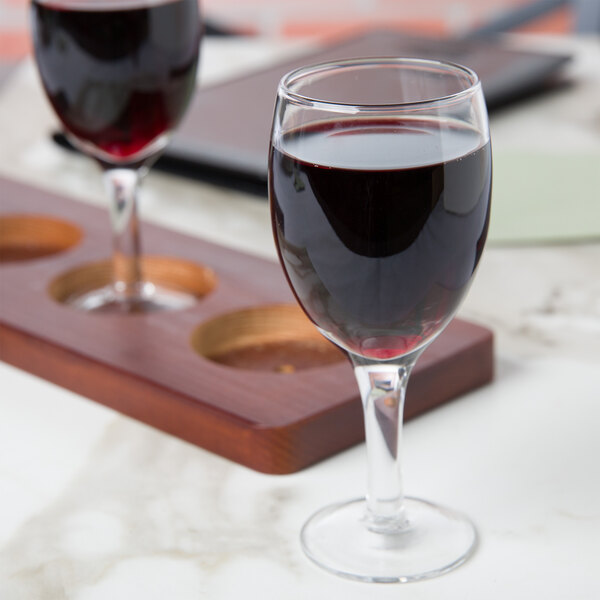 A close-up of an Anchor Hocking Perfect Portions wine glass with red wine on a table.