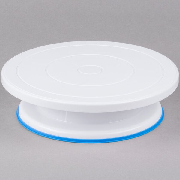 A white plastic Ateco cake turntable stand with blue trim.