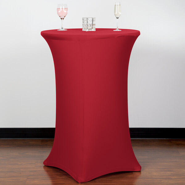 A crimson Snap Drape Contour bar height spandex table cover on a round table with two glasses on it.