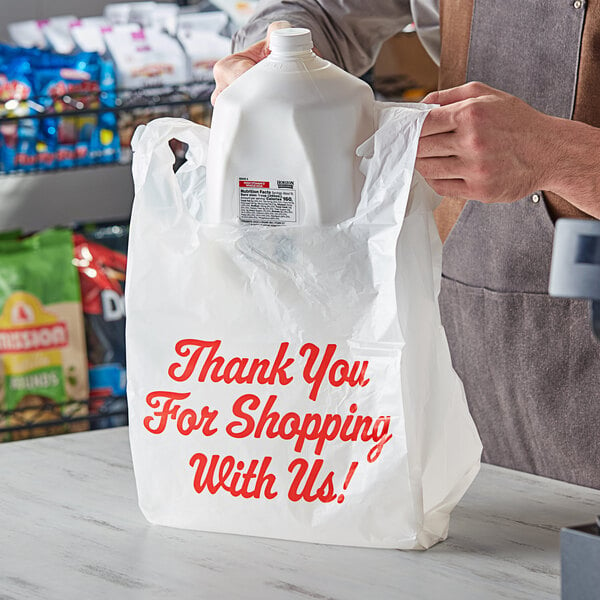 A person holding a white "Thank You" plastic t-shirt bag.