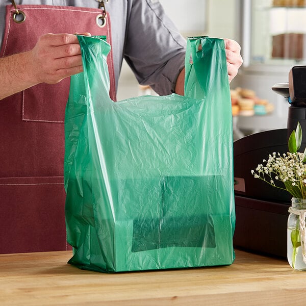A person holding a green plastic bag.