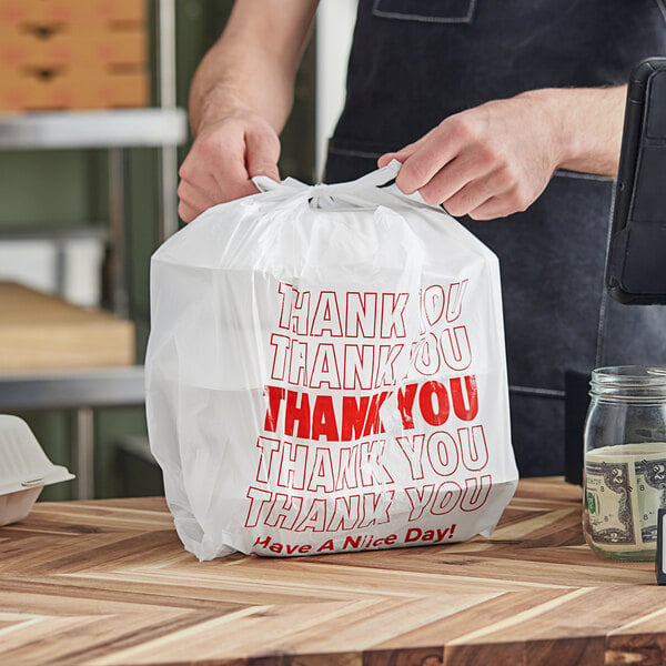A person holding a white plastic Choice "Thank You" bag.