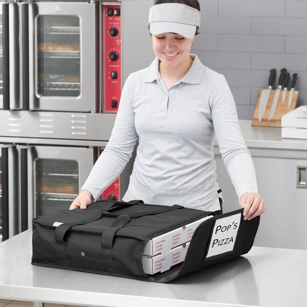 A woman holding a black Choice insulated pizza delivery bag with white pizza boxes inside.