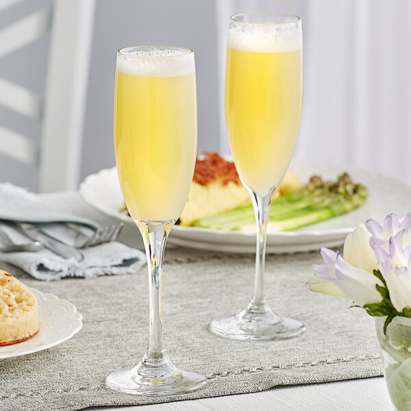 Two Libbey tall flute glasses of champagne on a table.