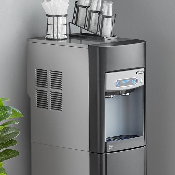 A Follett countertop ice maker and water dispenser with a cup holder on top.