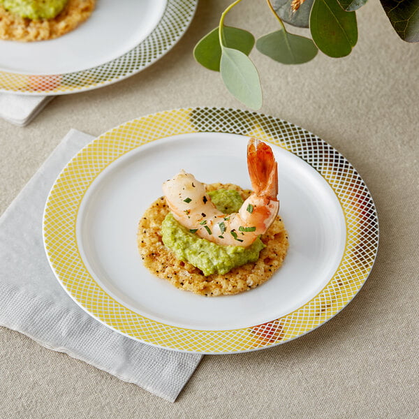 A Visions white plastic plate with a gold lattice design holding shrimp and avocado