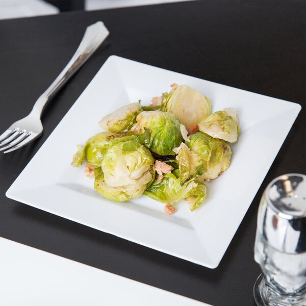 A Visions white plastic plate with brussels sprouts and a fork.