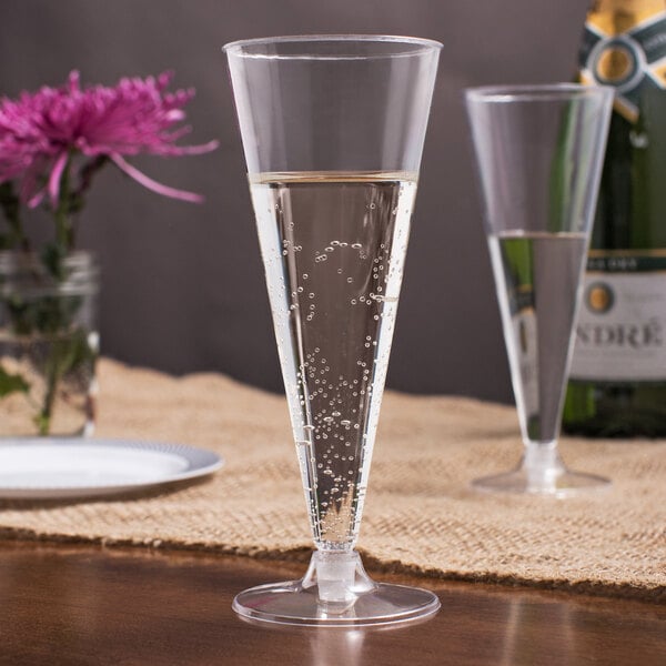 Two Visions plastic champagne flutes on a table with flowers.