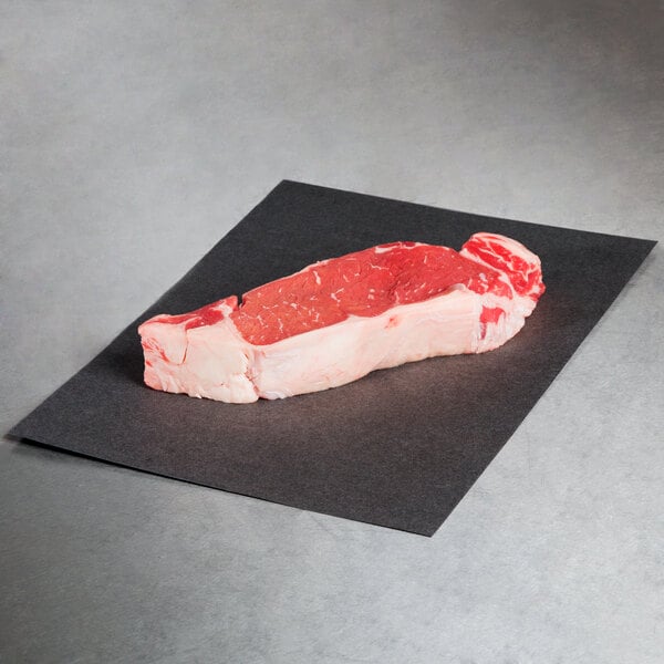 Choice black steak paper with a piece of meat on it.