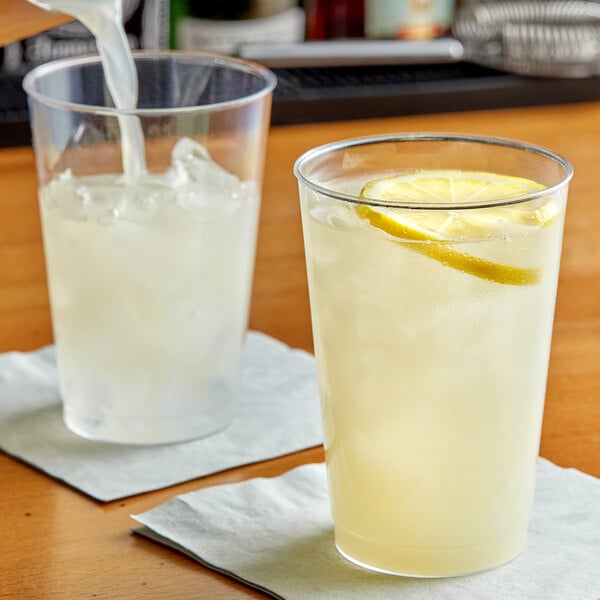 A clear plastic tumbler of lemonade with ice and lemon slices.
