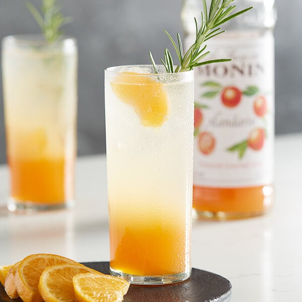A glass of Monin mandarin flavored orange juice with a rosemary sprig.