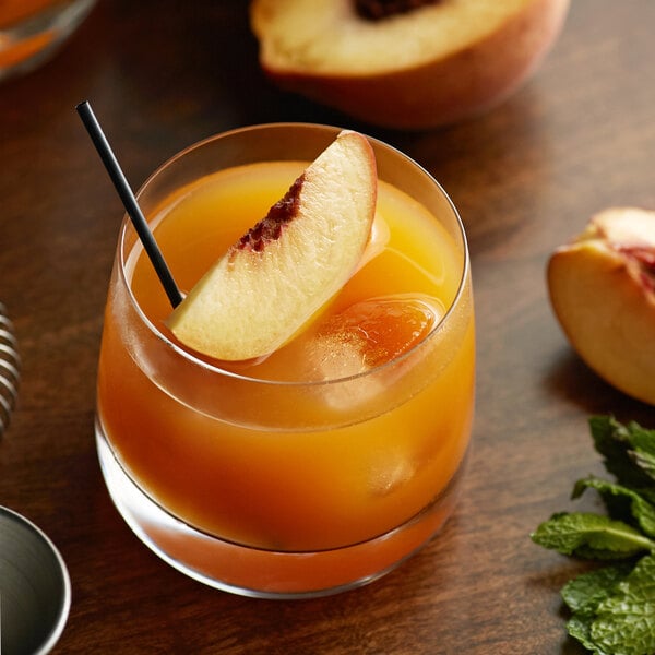 A glass of peach juice with a straw and a slice of peach.