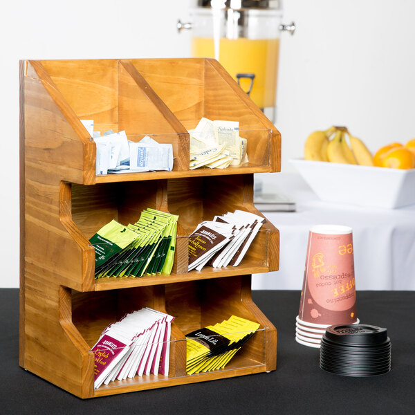 A Cal-Mil Madera rustic pine condiment display with clear bins holding packets on a wooden shelf.