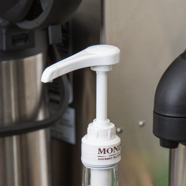 A white Monin syrup pump on a bottle.