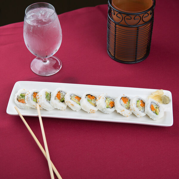 A CAC Bone White porcelain platter with sushi and a glass of water on it.